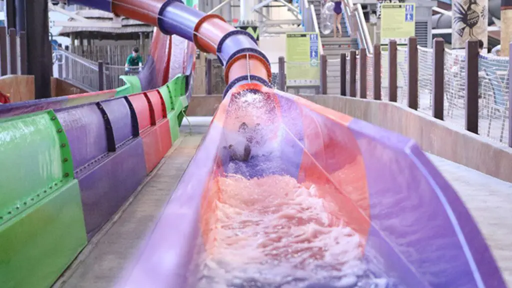 person going down a pink and purple slide at Kalahari Resorts waterpark