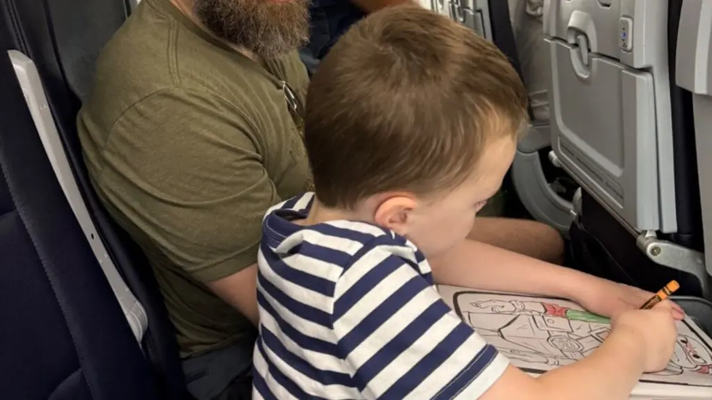 young child coloring on an airplane tray table