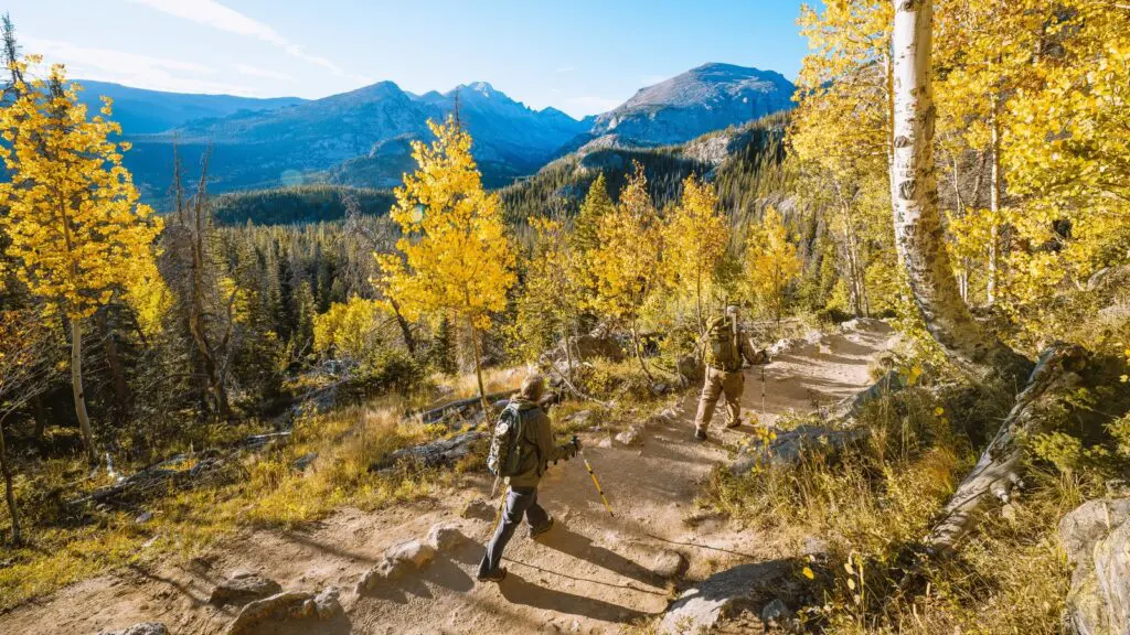 Dua orang mendaki dengan tongkat di area Estes Park pada musim gugur