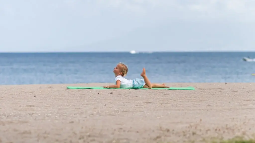 A little girl doing yoga on the beach