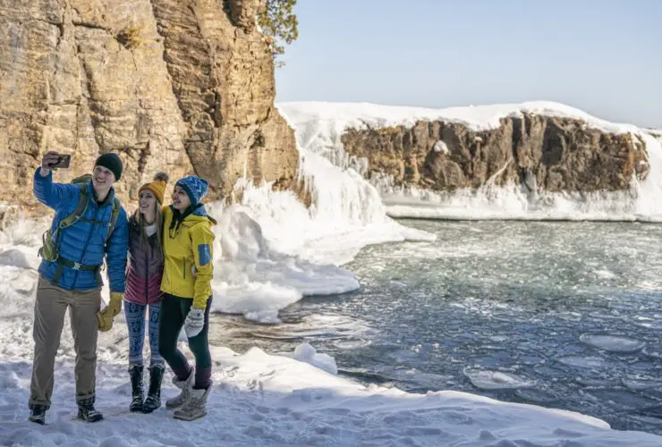 Three people taking a selfie during the winter at Presque Isle Park in Marquette County, Michigan