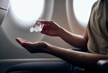 person using hand sanitizer in flight while taking steps to stay healthy on vacation
