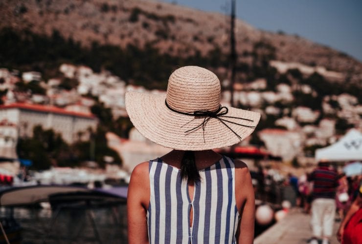 woman in straw hat and striped tank top on vacation