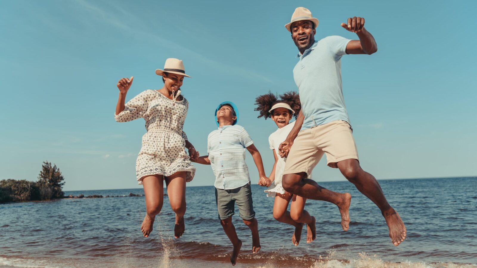 family jumping in the sand at the beach