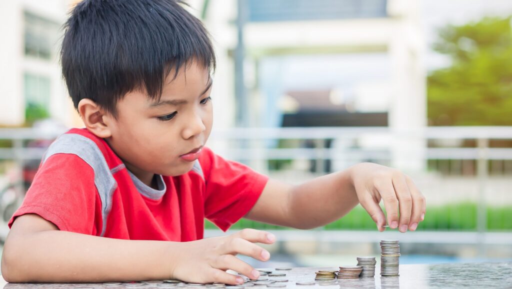 Child wearing backpack sitting at a table stacking coins