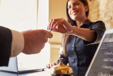 Guest takes room key card at check-in desk of hotel (Photo: Shutterstock)