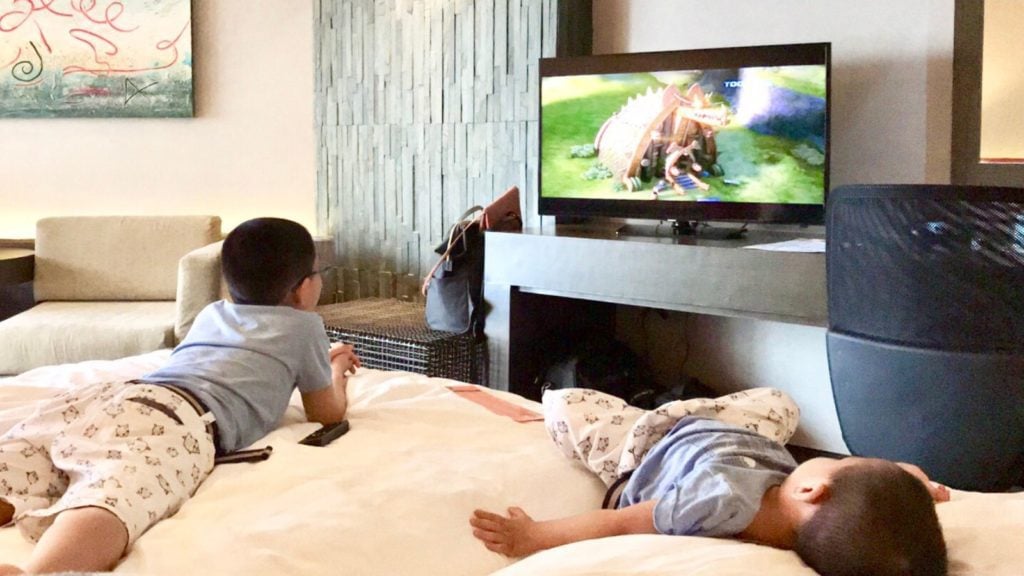 Kids watching TV inside a hotel room lying on the bed (Photo: @clyd_c81 via Twenty20)