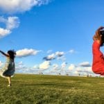 two women in dresses jumping: girls trips