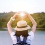 woman holding hands in a heart over the sun at sunset