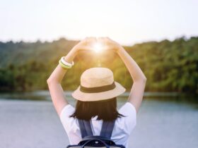 woman holding hands in a heart over the sun at sunset