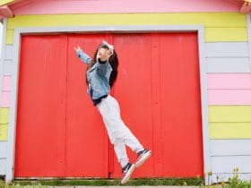 girl in sneakers jumping in front of colorful house
