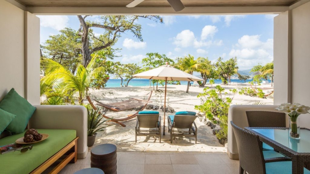 patio of suite at Spice Island Beach Resort all-inclusive beach resort with view of hammocks, umbrella, palm trees, and beach