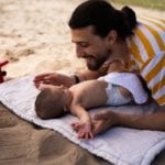 parent playing with baby at the beach: best baby sunscreens
