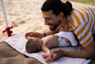 parent playing with baby at the beach: best baby sunscreens