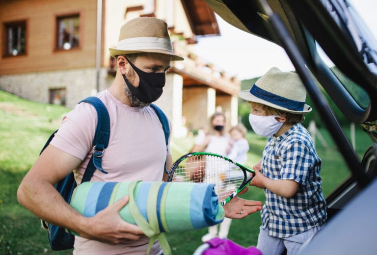 masked family packing a car to travel after the pandemic