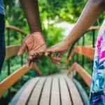 couple holding hands while walking over a bridge: best vacation spots for couples