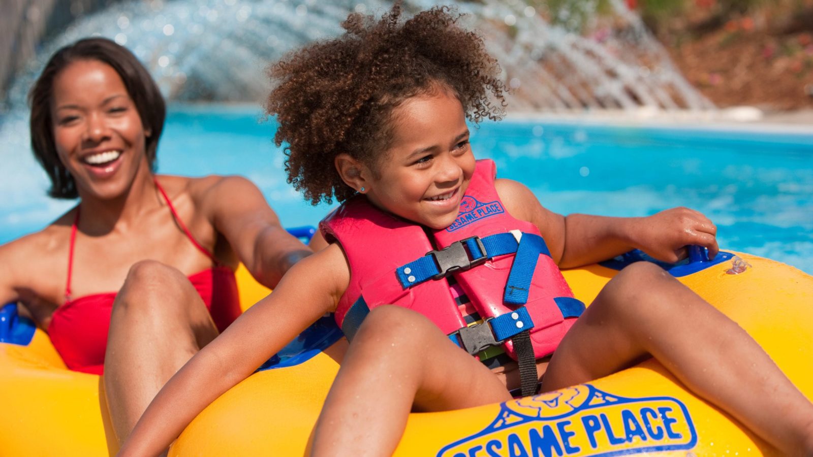 Child and parent floating down Rambling River at Sesame Place, an amusement park for young kids