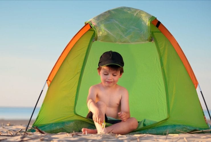Little boy playing near a beach tent (Photo: Levranii / Shutterstock)