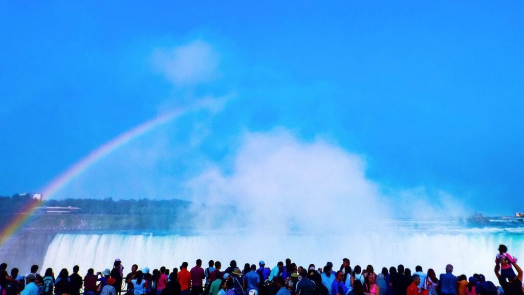 long line of tourists looking at Niagara Falls and rainbow