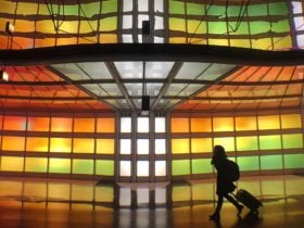 Person rolling luggage in front of stained glass display in airport terminal