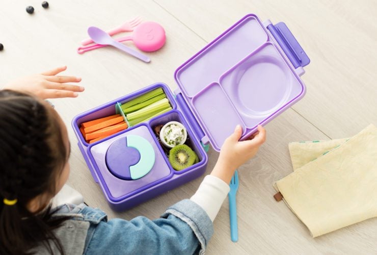 child looking into OmieBox bento box with food items inside