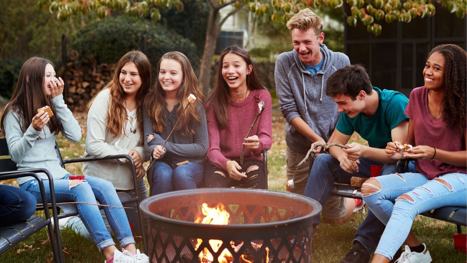 Teenagers roasting marshmallows around a fire pit (Photo: Shutterstock)