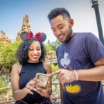 Two people at Disneyland looking at their phones