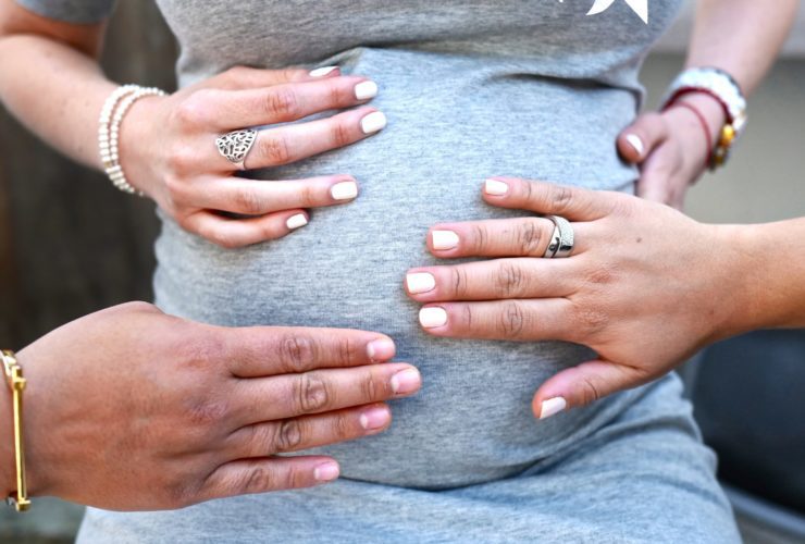 woman wearing a maternity dress with hands touching her pregnant belly