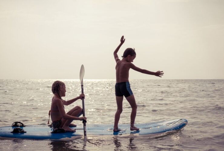 kids playing on a paddleboard in the water