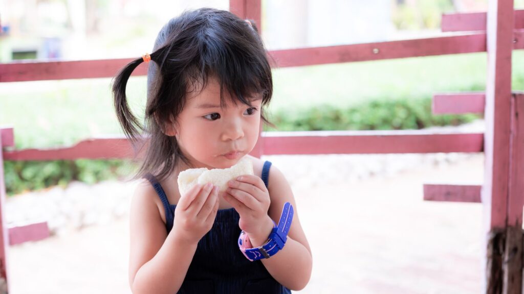 young child on vacation eating a sandwich