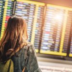 Woman in airport terminal looking at arrivals and departures board (Photo: Shutterstock)
