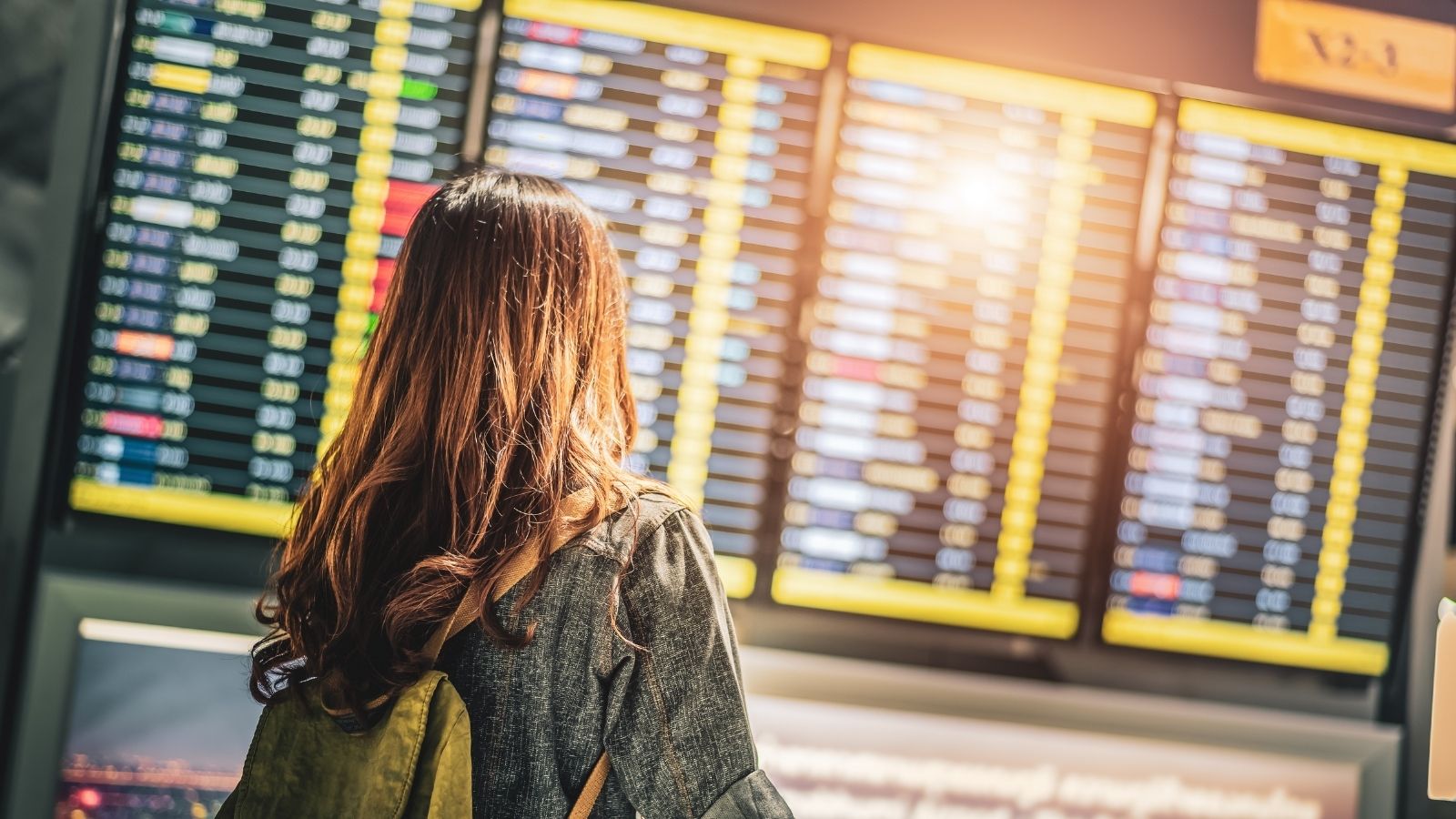 Woman in airport terminal looking at arrivals and departures board (Photo: Shutterstock)