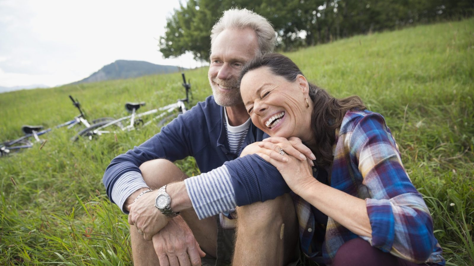 Laughing senior couple relaxing near mountain bikes in remote rural field (Photo: Trafalgar Tours)