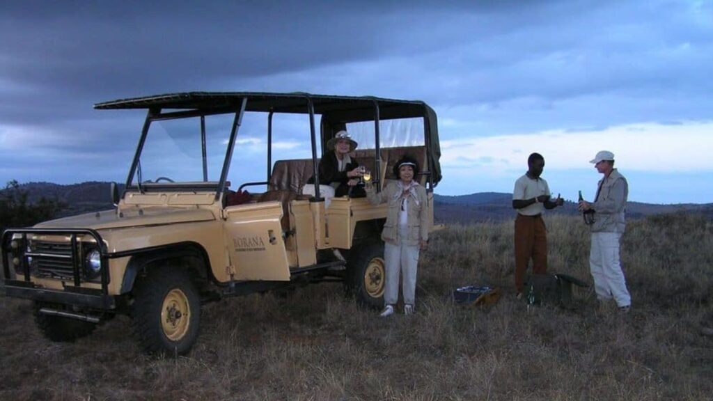 two women on a safari vehicle toasting with sparkling wine at dusk on a Globus tour
