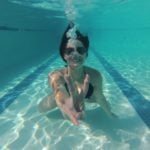 girls getaway in Palm Springs- woman underwater in pool showing peace sign