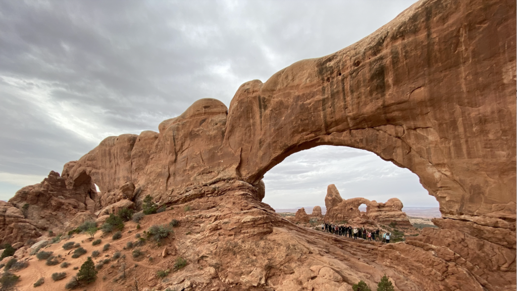 kelompok wisata di bawah bayang-bayang lengkungan Taman Nasional Arches