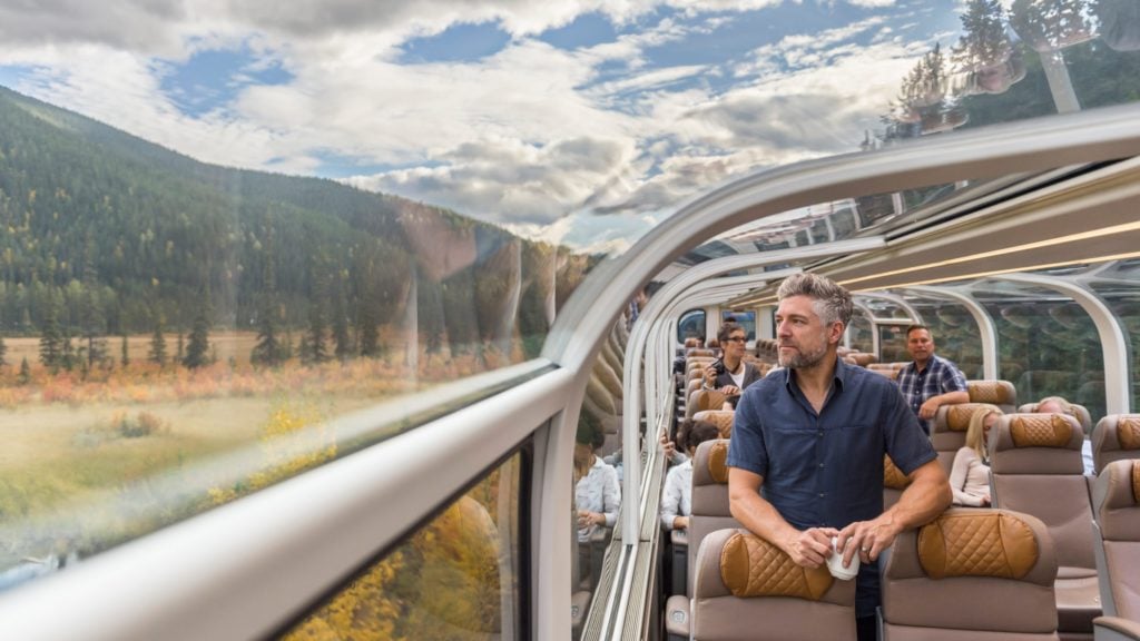 man looking out window in Goldleaf class aboard the Rocky Mountaineer train