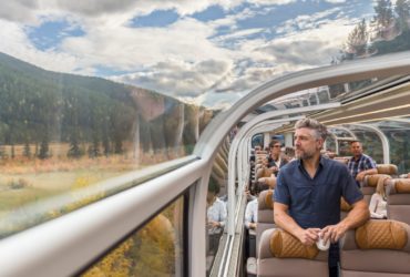 man looking out window in Goldleaf class aboard the Rocky Mountaineer train