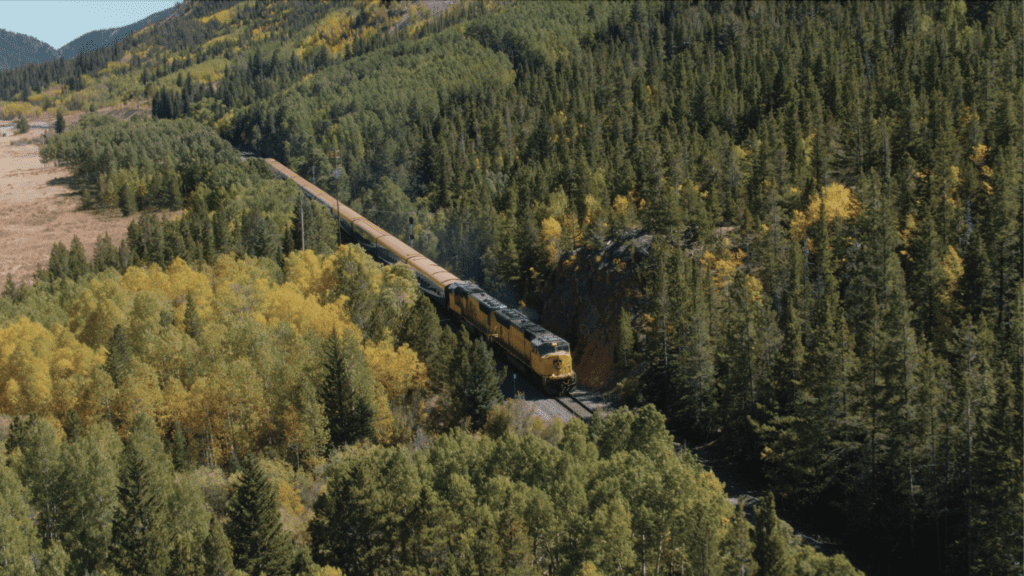 Rocky Mountaineer Rockies to Red Rocks train makes its way through a mountain forest