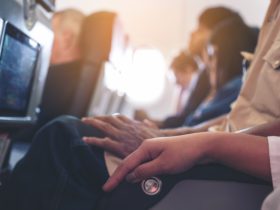 close up of person's arm on airplane armrest with people sleeping on a plane in the background