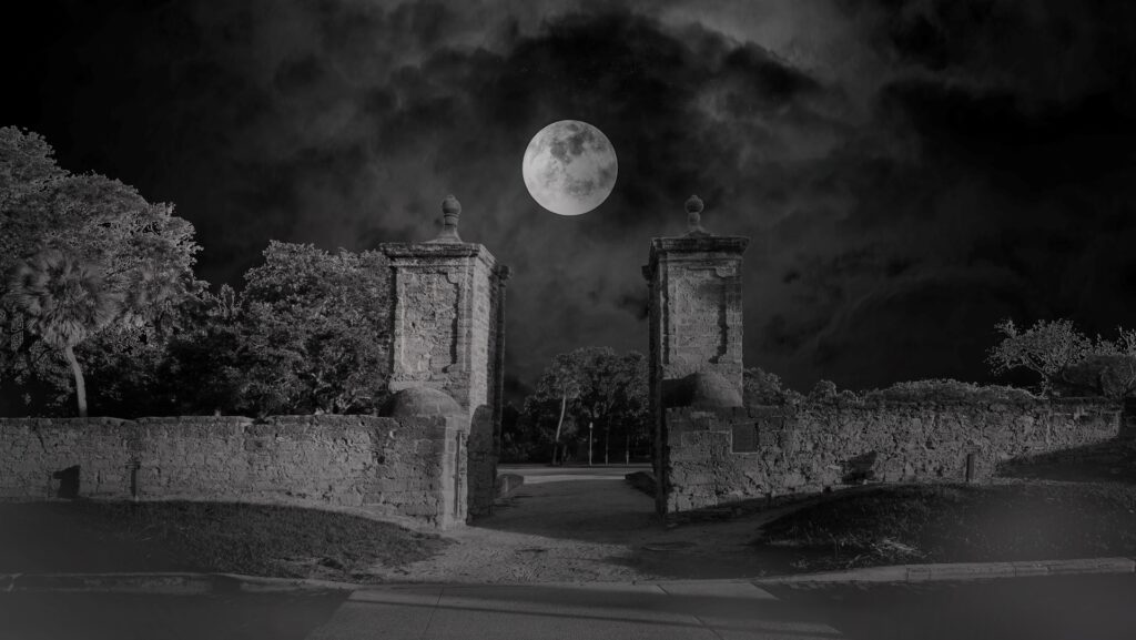 a black and white photo of a full moon over the St. Augustine city gates