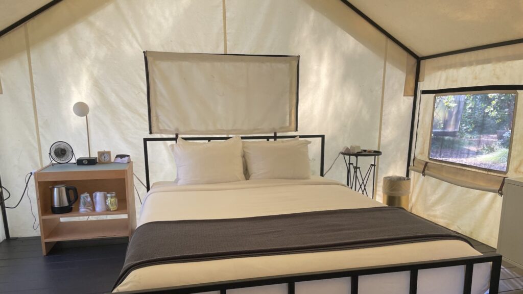 luxury tent interior with bed, lamps, side tables, and tea kettle at Autocamp Russian River