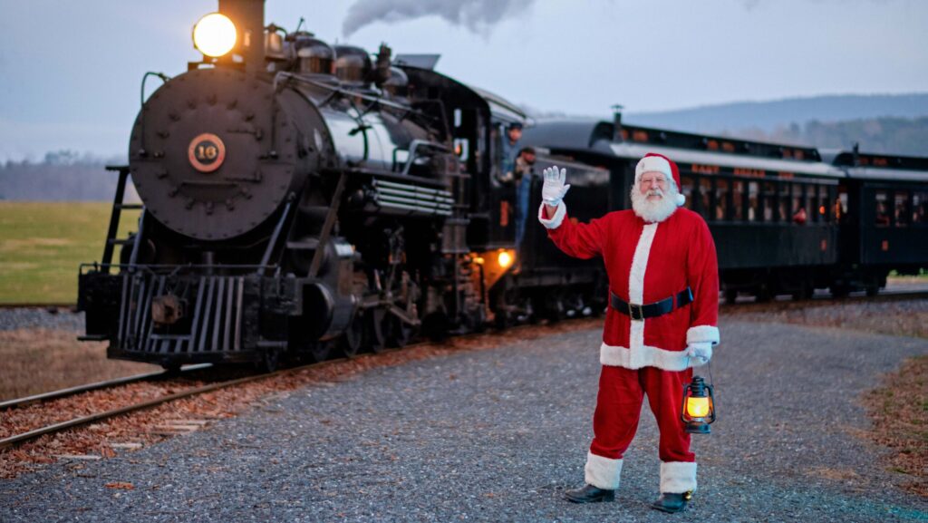 Santa Claus holding a lantern and waving in front of a train