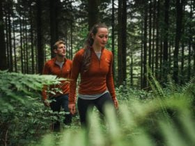 people walking through the forest wearing rust-colored Kora brand Yardang baselayers, which are warm and packable.