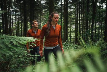 people walking through the forest wearing rust-colored Kora brand Yardang baselayers, which are warm and packable.
