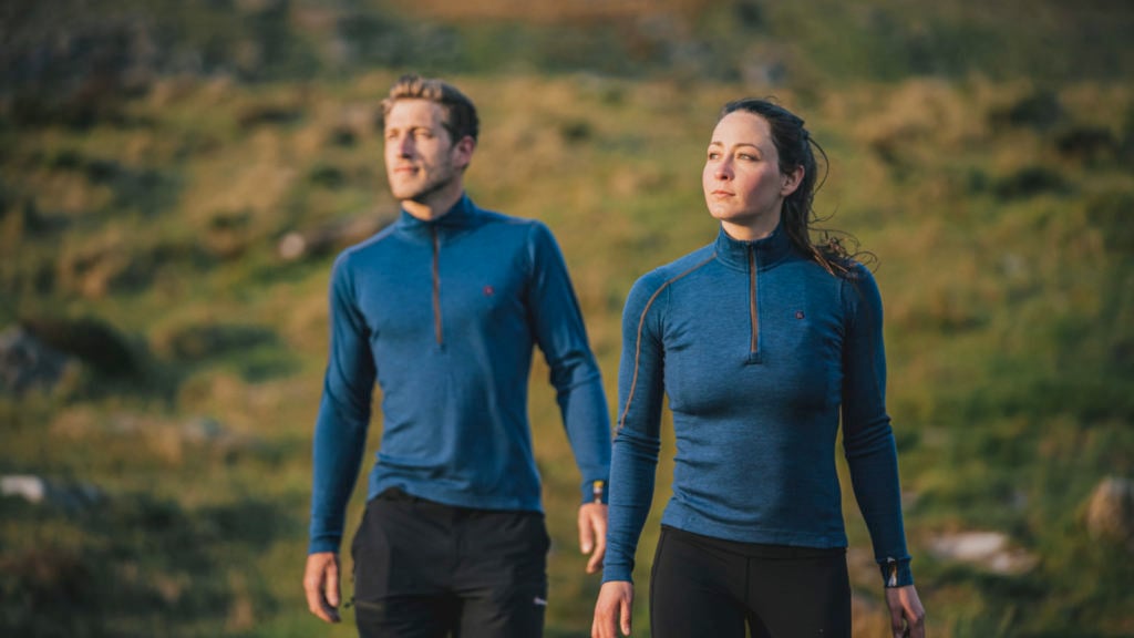 Two people standing in a field wearing Kora brand Yardang base layers