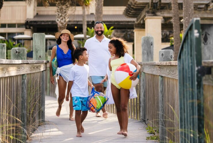 A family on a boardwalk heading to the beach with a beach ball
