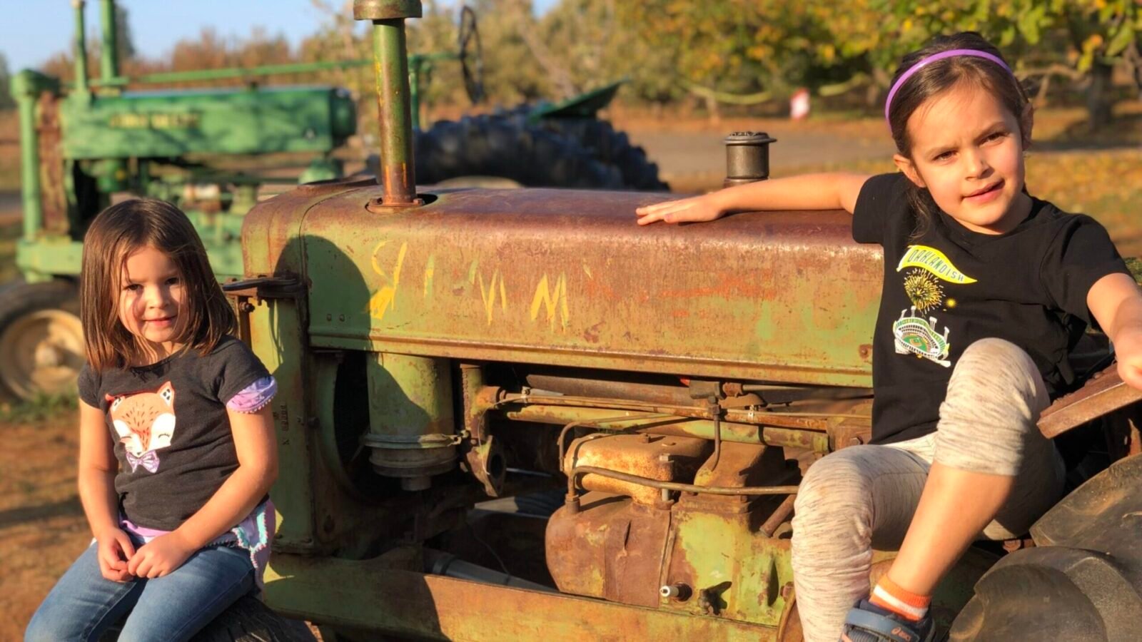 two children sitting on a tractor in Apple Hill at Rainbow Orchards