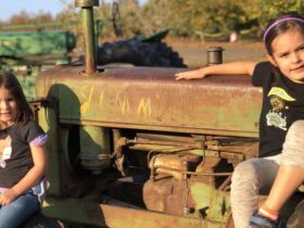 two children sitting on a tractor in Apple Hill at Rainbow Orchards