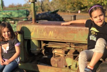 two children sitting on a tractor in Apple Hill at Rainbow Orchards